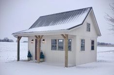 a small white building with a covered porch in the middle of a snow covered field