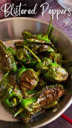 some green peppers in a silver bowl on a table with the words blistered peppers