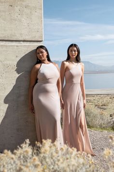 two women standing next to each other in long dresses