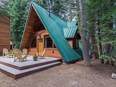 a small cabin in the woods with a deck and chairs