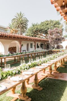 a long table with plates and glasses on it in front of an outdoor dining area