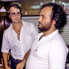 two men standing next to each other in a kitchen