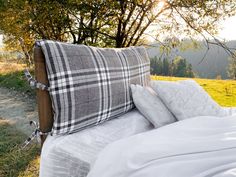 a bed with two pillows sitting on top of it next to a field and trees