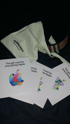 four cards with apple logos on them sitting next to a bag and some other items