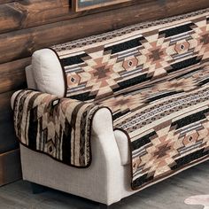 a couch covered in a blanket next to a wooden wall