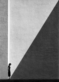 a person standing in front of a tall building with a shadow on it's wall