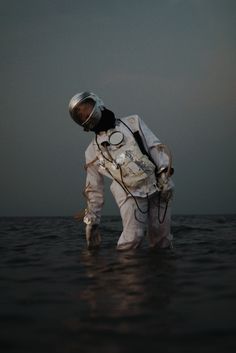 an astronaut standing in the water with his helmet on