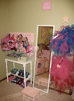 a room with a mirror, pink and blue dress up clothes on the shelf next to it