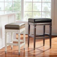 two stools sitting next to each other in front of a window with white trim