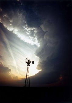 a windmill in front of a cloudy sky with a woman's face painted on it