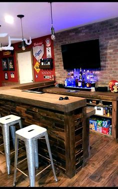 a bar made out of pallets with stools and a television mounted on the wall