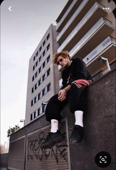 a man sitting on top of a wall next to a tall building