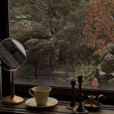 there is a cup and saucer on the window sill next to a mirror