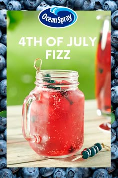 a glass jar filled with liquid next to blueberries