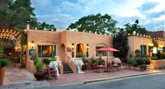 an outdoor restaurant with tables and umbrellas on the side of the road at dusk