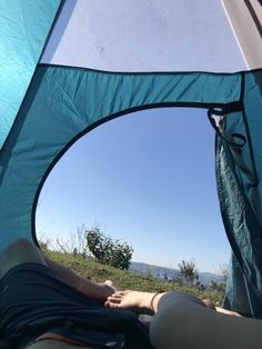 a person laying in a tent with their feet up on the ground looking out into the distance