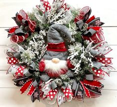 a christmas wreath with a gnome's hat and red, white and grey ribbons