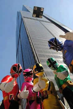 several people dressed in costume standing next to each other near a tall building with glass windows