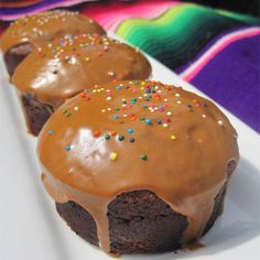 three chocolate cupcakes with frosting and sprinkles on a white plate