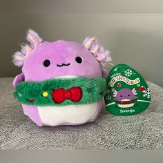 a purple stuffed animal with a green scarf around it's neck sitting on a table