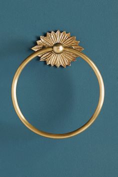 a gold ring on a blue surface with a flower design in the middle and a small round hole at the center