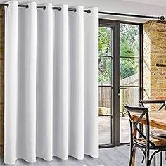 white curtains hanging on the side of a brick wall next to a dining room table