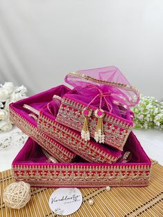 three pieces of pink and gold jewelry sitting in a box on top of a bamboo mat