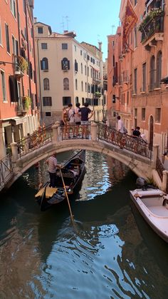 a gondola in the middle of a canal with several people on it and buildings lining both sides