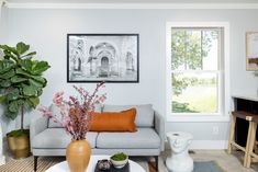 A living room decorated with a potted tree, a gray sofa, a large black and white photo and a modern side table against a light blue wall. Trending Home Design, Refresh Your Home, Manufactured Home, Popular Color, New Home Designs, Home Builders, Staging, Interior Designer, Home Design