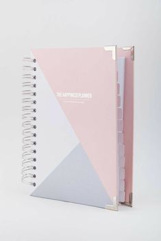 a pink and grey spiral notebook with the words happiness planner written on it in white lettering