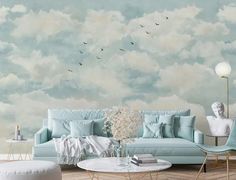 a living room with blue couches and clouds painted on the wall behind them,