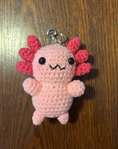 a crocheted keychain with a pink creature on it