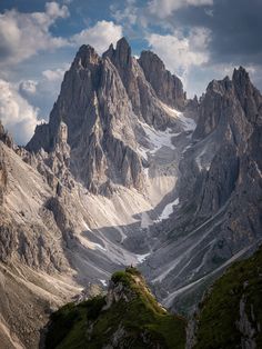 the mountains are covered in snow and green grass