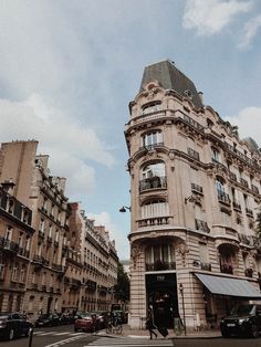 a tall building sitting on the side of a road next to cars and people walking