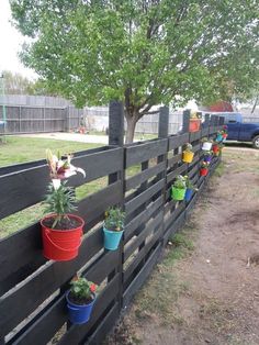 several potted plants are on the side of a fence