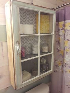 a bathroom with a toilet, cabinet and shower curtain in the corner on the wall