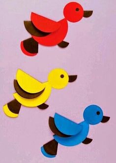 three different colored wooden ducks on a pink background