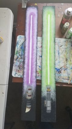 three different colored candles sitting on top of a table next to paintbrushes and other art supplies