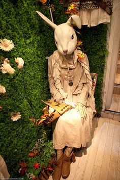 a rabbit sitting on top of a wooden bench in front of a wall covered with flowers