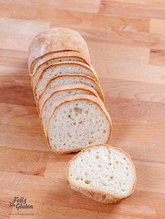 a loaf of bread sitting on top of a wooden cutting board next to slices of bread