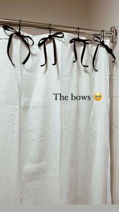 the bow shower curtain is hanging in front of a white tile wall with an emoticive message on it