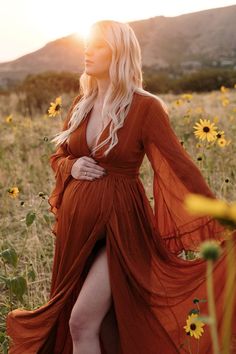 a woman in an orange dress is standing in a field full of sunflowers