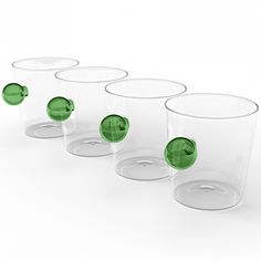 five glasses with green lids are lined up in a row on a white surface and one is empty