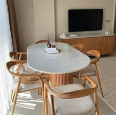 a white table with chairs and a television in the backround, next to a window