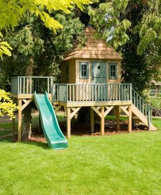 a tree house with a slide in the yard