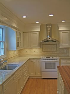 a kitchen with white cabinets and wood floors