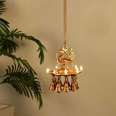 a gold colored chandelier hanging from a chain with three lit candles on it