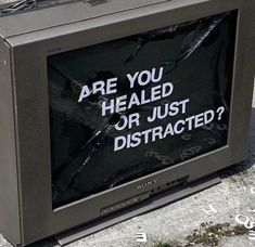 a tv sitting on the side of a road with a sign that says are you healed or just distracted?