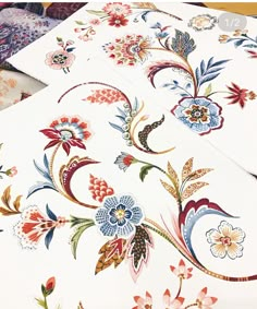 two sheets of white paper with colorful floral designs on the sides and bottom of each sheet