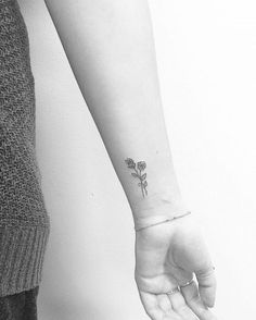 a woman's arm with a small rose tattoo on the left side of her wrist